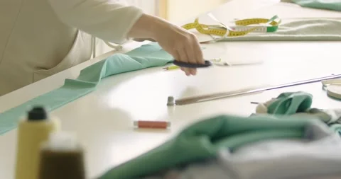 Female unknown designer cutting material with scissors on table while working Stock Footage 202517623