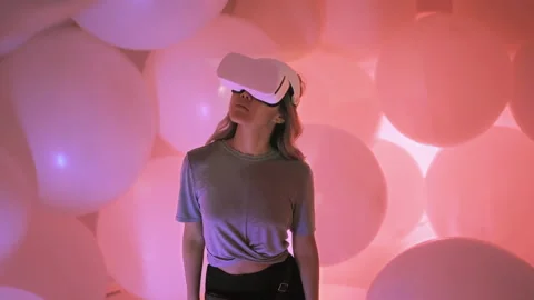 Female user of virtual reality glasses is exploring digital world around her Stock Footage 220307428