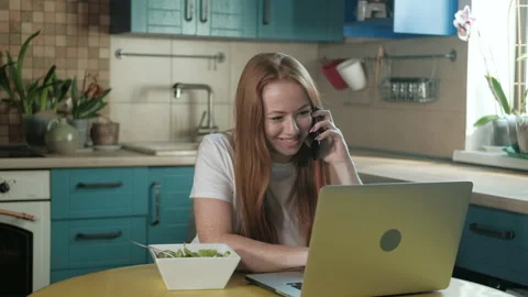 Female uses a computer in the kitchen and eats a vegetable salad Stock Footage 153167296