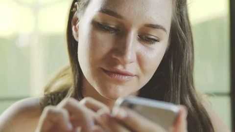Female using app on phone and smiling in cafe. Beautiful young casual woman writ Stock Footage 72979313