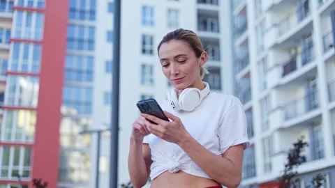 Female using gadgets during break between exercising process on fresh air Stock Footage 276454429