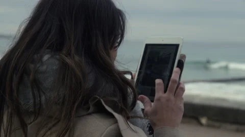 Female using a iPad at the beach to take a photo Stock Footage 65454617