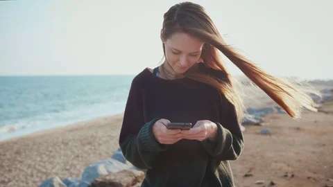 Female using mobile phone to text to beloved friend or couple using app on beach Stock Footage 100452199