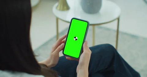 Female using phone while sitting on couch at home. Woman holding and looking at Stock Footage 151624792