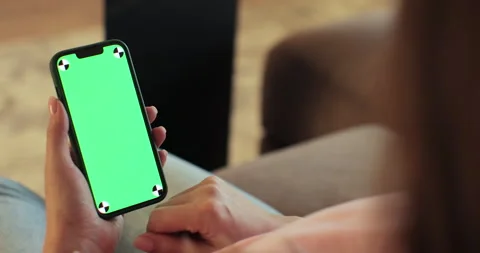 Female using smartphone with green screen mock up display at home. Browsing the Stock Footage 254157280