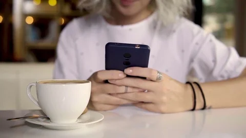 Female using smartphone while drinking coffee Stock Footage 83205343
