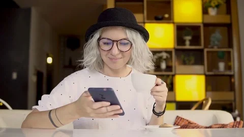 Female using smartphone while drinking coffee Video stock 83210614
