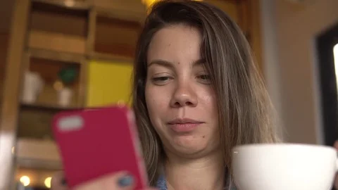 Female using smartphone while drinking coffee Video stock 84003156