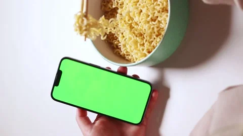 Female using smartphone while eating pasta at home. Green screen Stock Footage 289204598