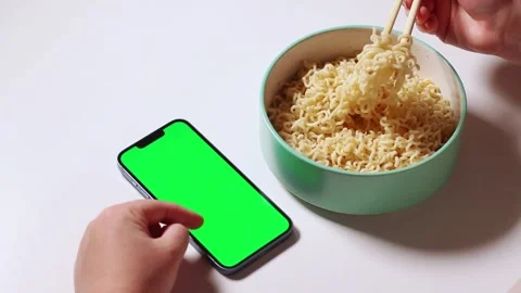 Female using smartphone while eating pasta. Smartphone with green screen Stock Footage 291716319