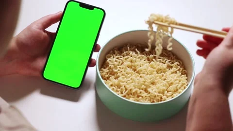 Female using smartphone while eating pasta. Smartphone with green screen Stock Footage 291716330