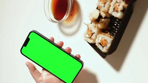 Female using smartphone while eating sushi rolls at home. Green screen Stock Footage 292116958
