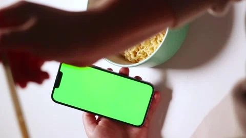 Female using smartphone while eating pasta at home. Green screen Stock Footage 295141004