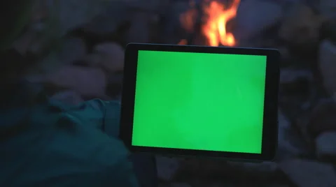 Female using Tablet by a Camp Fire with Green Screen. Stock Footage 63347509