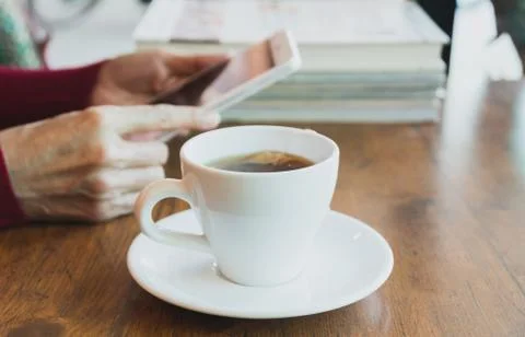 Female using a tablet with tea cup on wooden table. Stock Photos