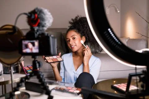 Female vlogger recording a makeup tutorial, applying cosmetics with brush Stock Photos