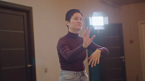Female vocal coach conducting studio rehearsal, short hair gesturing, warm light Stock Footage 346552462