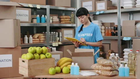 Female volunteer using clipboard while working at food bank Stock Footage 183970417