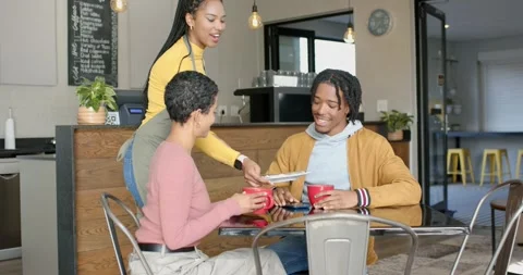 Female waitress carrying tray serving plate, African American couple smiling Stock Footage 339558138