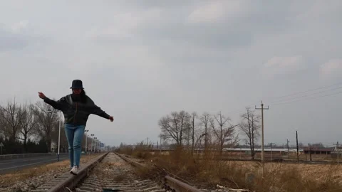 Female walking with open arms on open railroad track Stock Footage 331721927