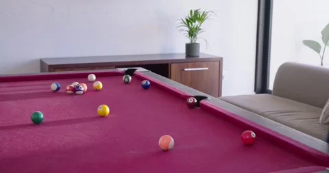 Female walking to red-felt pool table after break, inspecting balls and raising Stock Footage 337730197