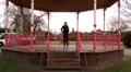 Female walks away from bandstand and answers her phone HD Footage