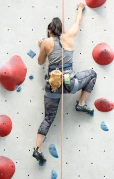 Female wall climber while climbing a high wall. Wall climbing sports by a fem Foto stock