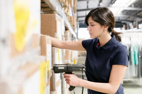 Female warehouse worker using barcode scanner on box in distribution warehouse Stock Photos