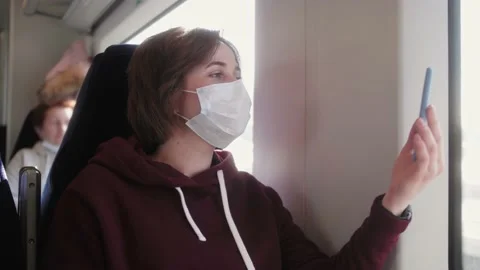 Female wearing face mask in train using mobile phone for video chat online with Stock Footage 152257525