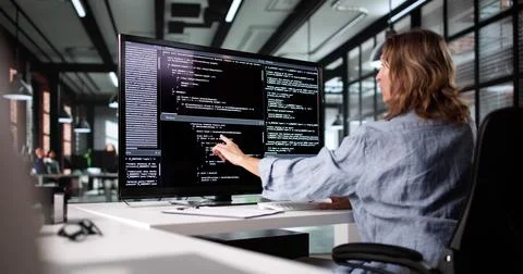 Female Web Developer Working On Software Code At Office Desk Stock Photos