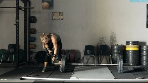Female weight lifter loading weights onto a bar in the gym Stock Footage 114988044
