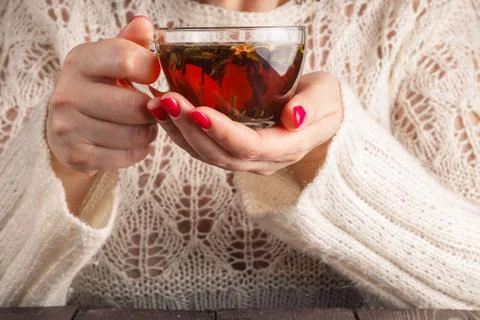 Female in white openwork pullover hold cup of tea Stock Photos
