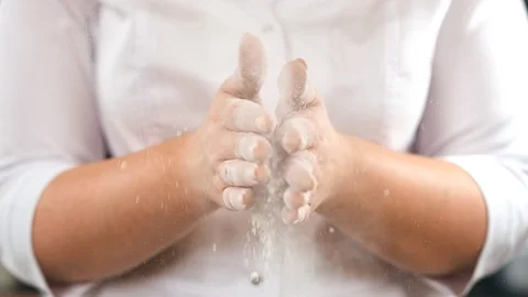 Female in white uniform clapping hands covered by flour slow motion. Close up Stock Footage 124155349