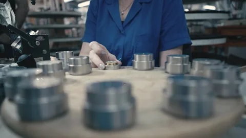 Female Worker assembling metal speaker parts on a rotary table inside a Stock Footage 320877398