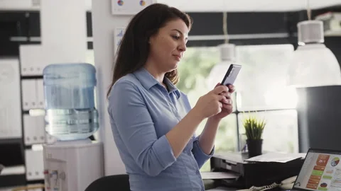 Female worker browsing website on mobile phone Stock Footage 236587940