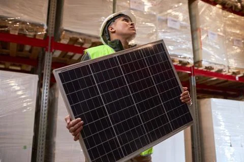 Female worker carrying solar panel at indoor warehouse Stock Photos