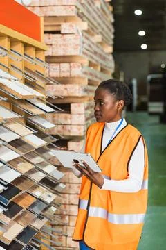 Female worker checking wood samples with digital tablet in lumberyard Stock Photos
