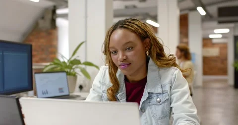 Female worker in denim jacket glancing at laptop leaning in studying at office Stock Footage 341061795