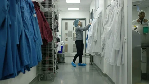 Female worker dressing up in uniform before going to production area Stock Footage 107964296