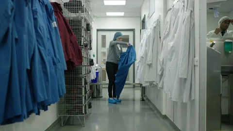 Female worker dressing up in uniform before going to production area Stock Footage 107964502