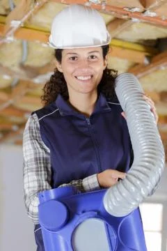 Female worker fitting ventilation system in buildings ceiling Stock Photos