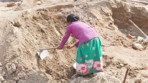 Female worker gathering soil with the help of a spade in a sunny afternoon Stock Footage 77447752
