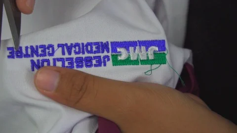 Female worker hand cutting thread on staff uniform Stock Footage 114986039