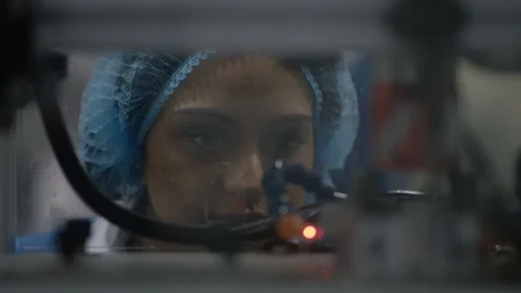 Female worker observing cosmetic boxes on production line through glass Video stock 107995356