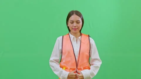 A female worker putting on a high-visibility orange safety vest over her work Stock-Footage 332057557