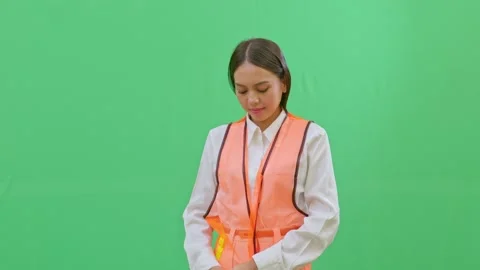A female worker putting on a high-visibility orange safety vest over her work Video stock 332057715