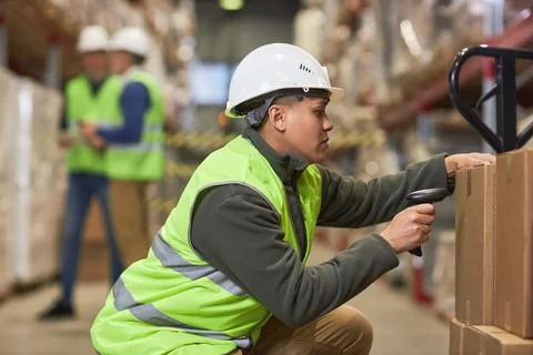 Female worker scanning codes on boxes in storage warehouse Stock Photos
