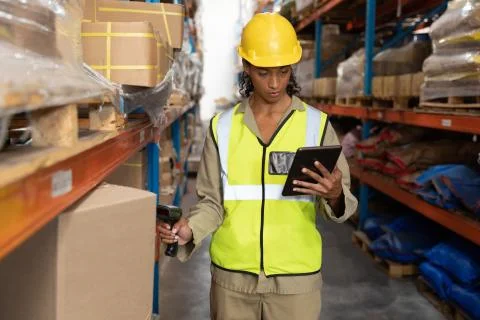 Female worker scanning package with barcode scanner while using digital tablet Stock Photos