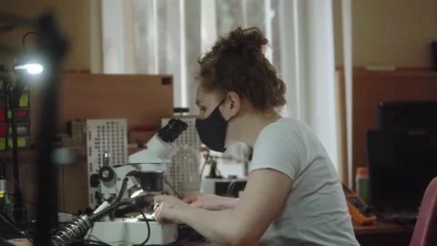 Female worker at a service center using microscope and to electronics circiuit Video stock 201145334