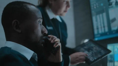 Female worker talks with security officer, uses tablet with surveillance footage Stock Footage 281720761
